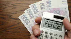 Výpočet penze kalkulačkou s českými bankovkami na dřevěném stole.