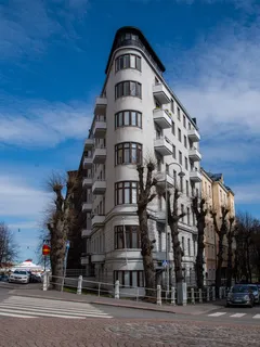 Moderní budova v Helsinkách s obloukovým rohem a modrou oblohou