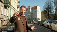 Realitní makléř s klíčem před domem, prodej nebo pronájem bytu ve městě.