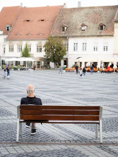 Muž sedící na lavičce v centru města Sibiu, Rumunsko