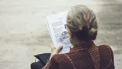 žena v hnědém topu čte papír