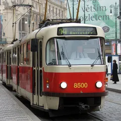 Červenobílá tramvaj číslo 14 v centru Prahy na městské ulici s cestujícími.
